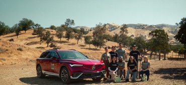 Acura ZDX driving down dirt road in grassy, brush-covered hills