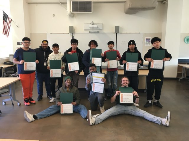 Students holding certificates in a classroom.