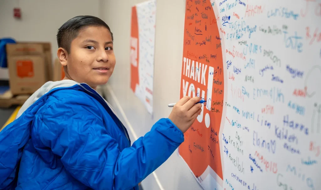 A student signing his name on a sign.