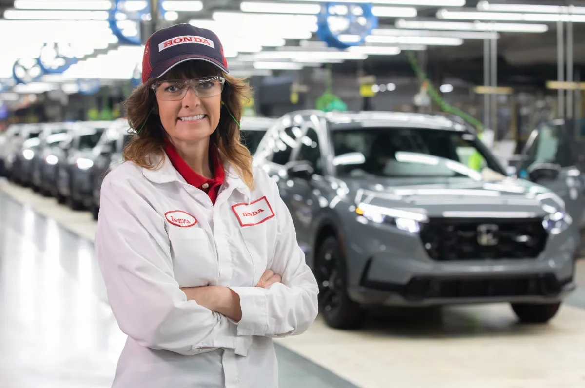 A Honda employee smiling at the camera on the vehicle assembly line