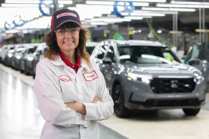 A Honda employee smiling at the camera on the vehicle assembly line