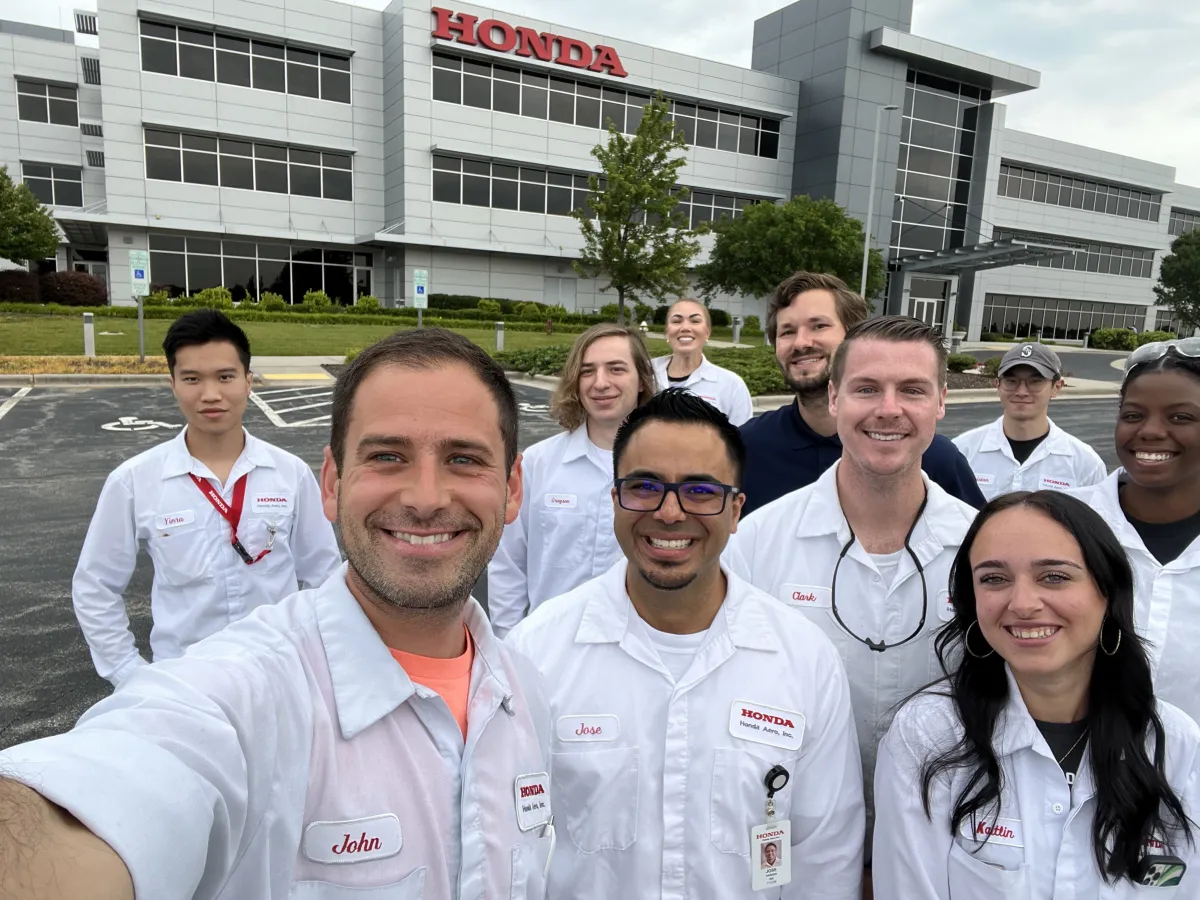 A group of Honda associates taking a selfie in front of a Honda building.