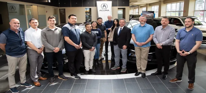 Group of people standing in front of Acura cars