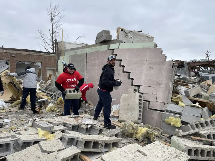 Volunteers cleaning up building rubble.