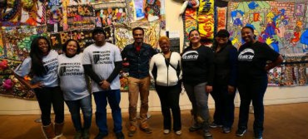 People standing in front of a painted wall.
